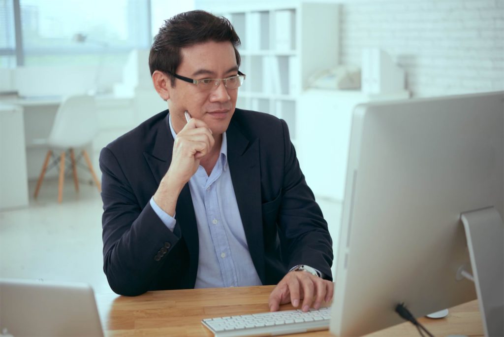 Man in glasses and suit looking at a computer