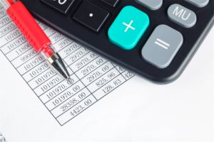 A financial report, with a red pen and a calculator on top of it