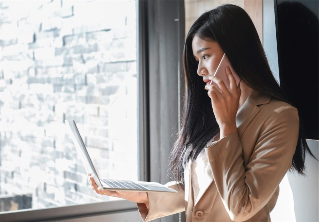 a businesswoman calling at the window while holding a laptop