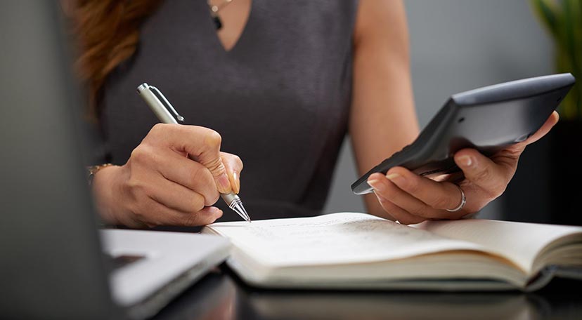 working-business-lady-holding-a-calculator-and-writing-in-a-notebook