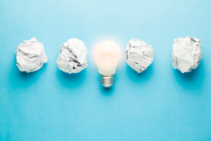 Light bulb in the middle of crumpled paper balls showing that an idea is what you need to start a business in Singapore