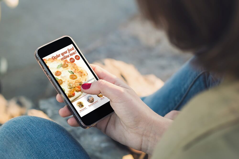 Woman ordering food on a mobile app launched by a company using business loans