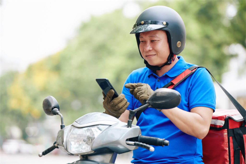 Delivery man accepting a delivery order on his motorcycle funded with a car loan