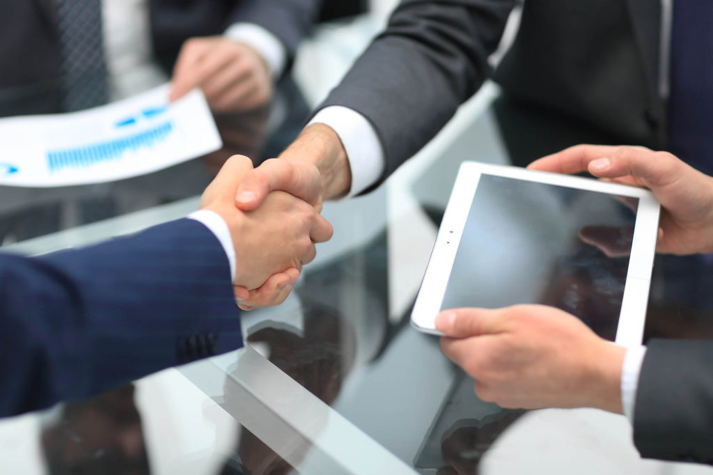 Two individuals shaking hands after signing a hire purchase agreement